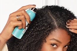 woman spraying cover up into her hair line