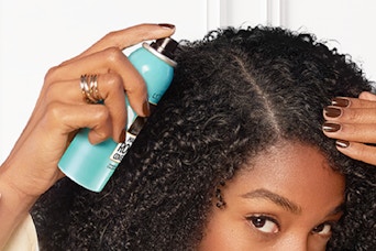 woman spraying cover up into her hair line