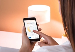 a person using her smartphone to turn on a lamp