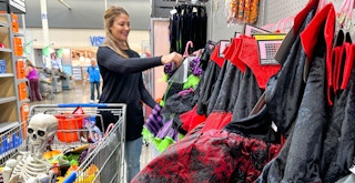 a woman looking at halloween costumes in walmart