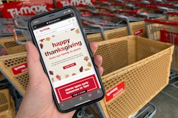 A cell phone in front of the TJ Maxx store with an annulment stating TJ Maxx will be closed on Thanksgiving.