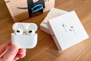 apple air pod pro being held next to amazon box