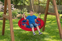 Lifestyle image of a Superman saucer swing being used outdoors by small child