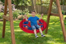 Lifestyle image of a Superman saucer swing being used outdoors by small child