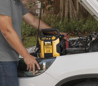 Everstart Maxx Jump Start sitting on top of vehicle while person uses it