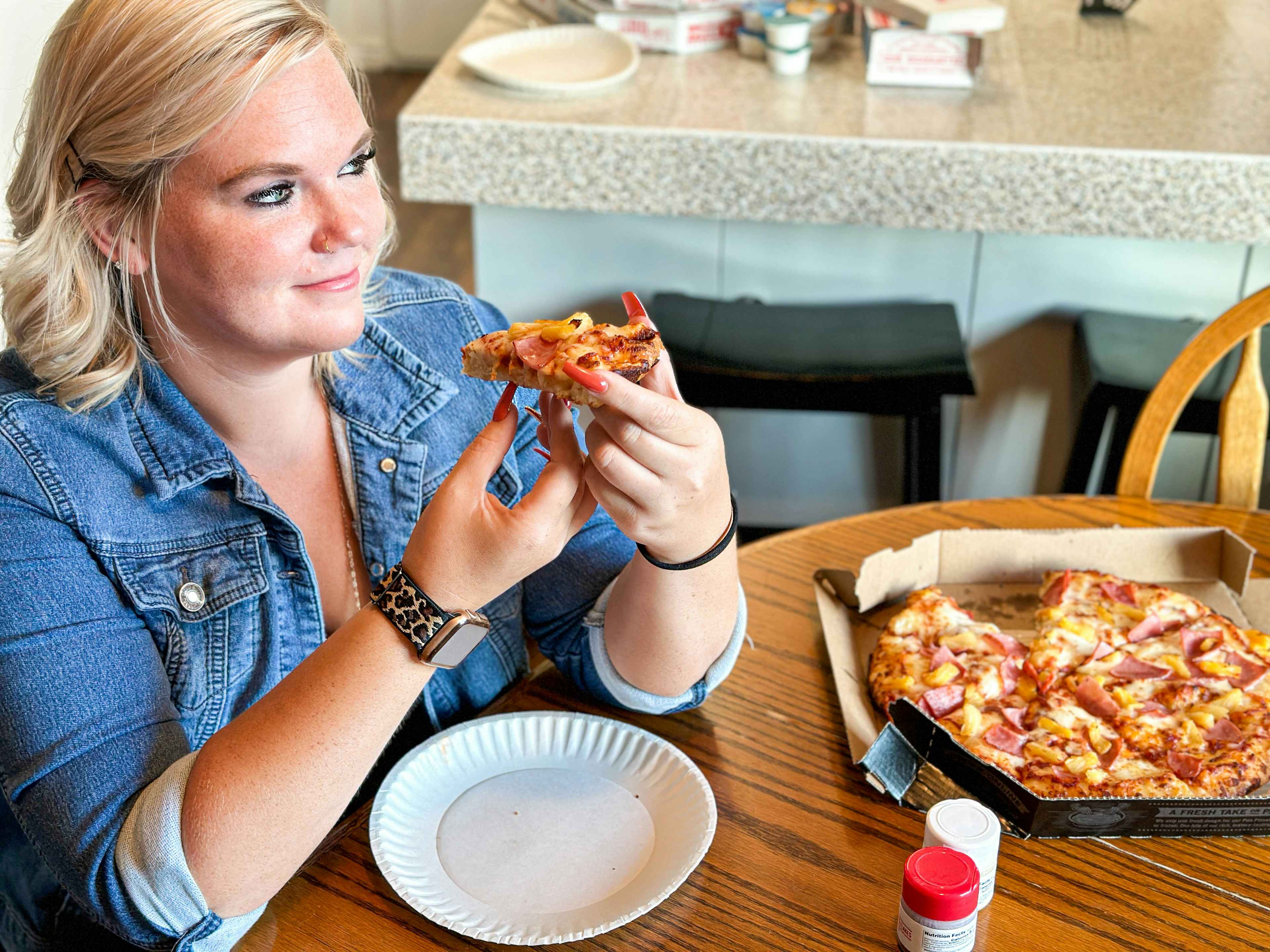 a woman eating pizza at the dinner table 