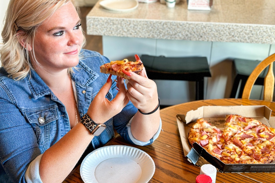 a woman eating pizza at the dinner table 