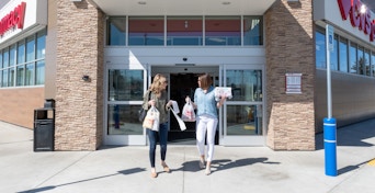 two people with shopping bags walking out cvs exit
