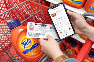 A person's hands holding a cell phone displaying 10% off Tide laundry detergent on the target circle app and a $2 off manufacture ...