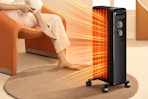 Lifestyle image of the black Cowsar Space Heater being used indoors near someone sitting in a chair