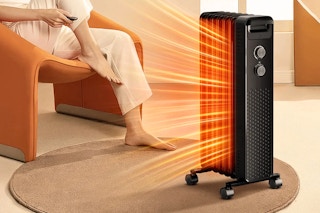 Lifestyle image of the black Cowsar Space Heater being used indoors near someone sitting in a chair