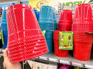 Someone holding some Giant Yard Pong cups in front of a shelf of the games at Five Below