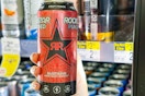 person holding a rockstar energy drink in the cooler