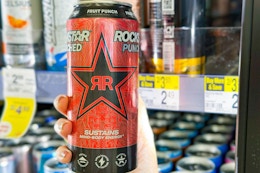 person holding a rockstar energy drink in the cooler