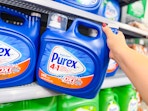hand taking a Purex detergent container off the shelf