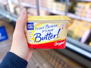 hand holding a tub of i cant believe it's not butter