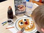 a child eating a ihop scary face pancakes signage in restaurant
