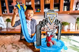 Lifestyle image of the Monster Jam Mud Blasters Monster Mutt Dalmatian Dunk Tank Playset (boy playing with it in kitchen setting)