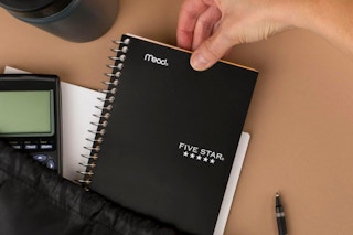 Person pulling Five Star Spiral Notebook out of bag