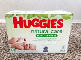 A box of Huggies Natural Care Sensitive Baby Wipes on a carpet floor.