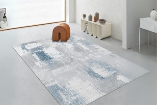 An abstract-patterned area rug sits in the center of a room.