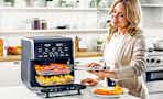 Lifestyle image of woman using the Gourmia All-in-One 14-Quart Air Fryer in kitchen setting