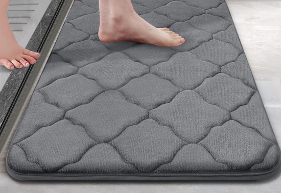 person stepping onto a gray memory foam bath rug