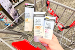 hand holding neutrogena sunscreens over a cvs shopping cart