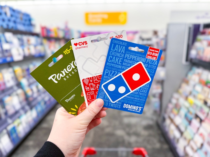 person holding 3 gift cards in an aisle