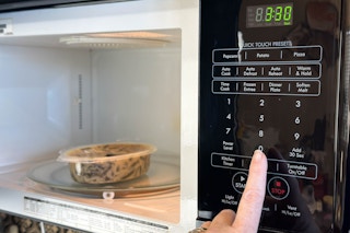 someone putting a bob evans farmhouse favorites side into the microwave