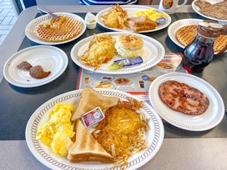 A Waffle House table covered in plates of breakfast food.