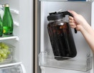 a person putting a pitcher of coffee in the fridge 