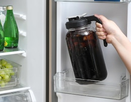 a person putting a pitcher of coffee in the fridge