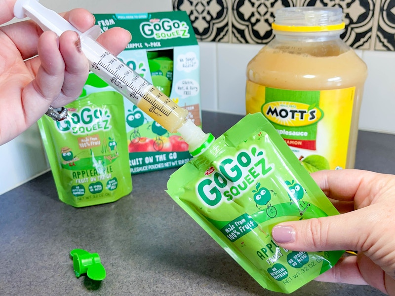 a person refilling an applesauce pouch with a syringe