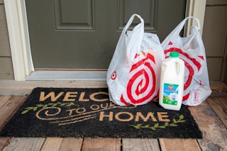 A Target Shipt grocery delivery order sitting on a front porch doormat that reads, "Welcome to our Home"