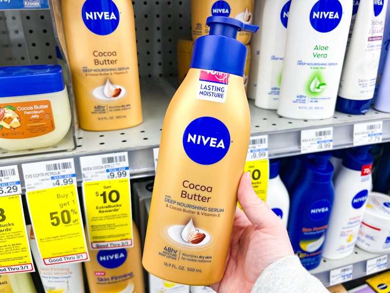 person holding nivea cocoa butter lotion in front of the shelf