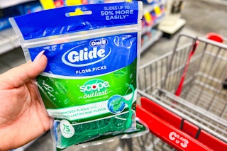 hand holding bag of oral-b floss picks in front of shopping cart