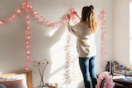 a woman putting up string lights