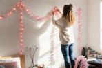 a woman putting up string lights