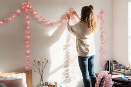 a woman putting up string lights