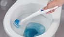 a hand cleaning a toilet with a toilet scrubber