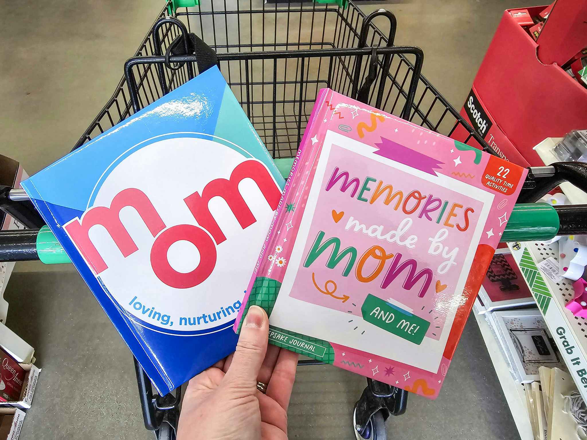 person holding 2 mom and me memory books over a cart