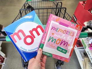 person holding 2 mom and me memory books over a cart