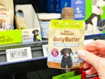 hand holding a tube of pet naturals calming peanut butter in walmart aisle
