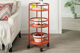 Lifestyle image of a red 3-tier rolling cart in a bedroom setting