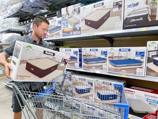 man putting a air mattress box in walmart cart