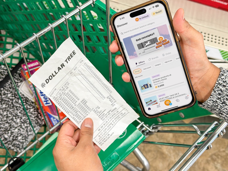 a person holding an iphone with a coupon app in the dollar tree store