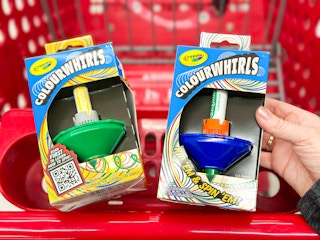 hand holding a box of crayola colourwhirls with another one in target cart