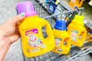 hand placing bottle of laundry detergent in shopping cart