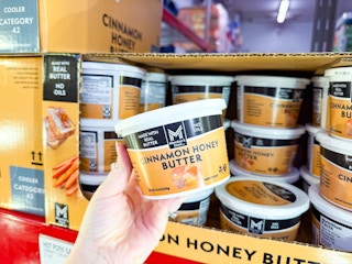 hand holding up a tub of butter at a grocery store